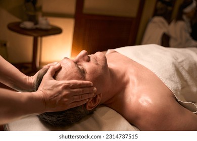 Qualified masseuse giving head massage to adult man