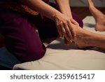 Qualified masseuse giving traditional Thai feet massage to her client