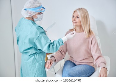 Qualified Medical Lab Technician Collecting Mucus From The Female Patient Nose For A PCR Test