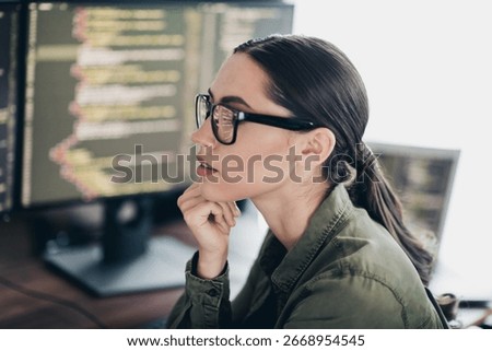 Qualified specialist programmer working on coding tasks using multiple monitors in a modern office setting