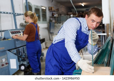 Qualified workman working with glass in industrial workshop