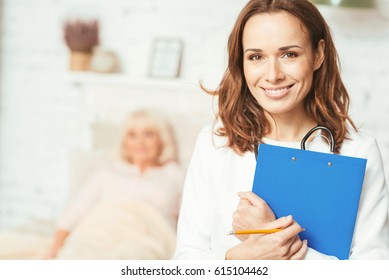 Qualified young therapist standing and holding folder in the hospital