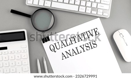 QUALITATIVE ANALYSIS written on paper with office tools and keyboard on grey background