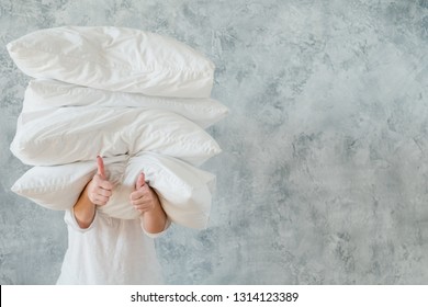 Quality bedding. Approval and thumbs up. Satisfied woman holding pile of pillows.