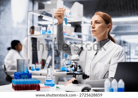 Quality control analyst in lab inspecting blue liquid clarity in test tube against light. Laboratory worker verifying chemical purity standards for industrial product manufacturing process