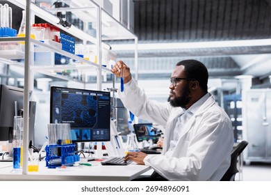 Quality control analyst using laboratory glassware filled with indicator solution at workstation in research facility. Lab staff member looking at sample tube with chemical fluid used for experiments