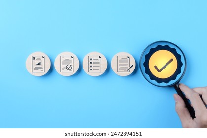 Quality Control and Certification Assurance Concept. Hand holding magnifying glass over checkmark symbol, alongside icons representing quality control, certification, and assurance on blue background.
