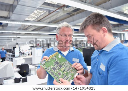 quality control in engineering in teamwork - employees at a meeting - production of electronics in a modern industrial factory 