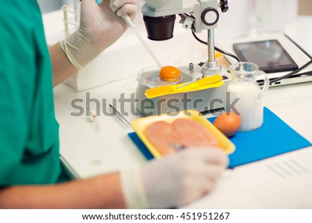 Quality control expert inspecting at chicken eggs in the laboratory, selective focus