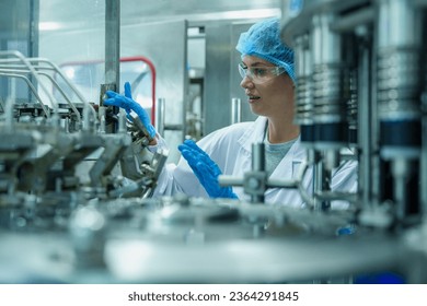 Quality control female factory worker inspecting quality in professional uniform working of drinking water bottling plant or drinking Water production plantsentence, water recycling. - Powered by Shutterstock