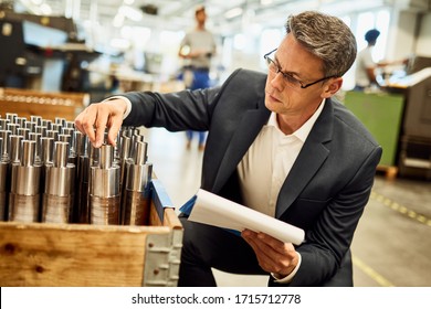 Quality control inspector examining manufactured steel cylinders in industrial building.  - Powered by Shutterstock