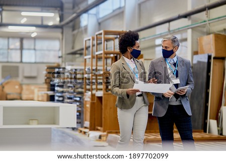 Quality control inspectors communicating while vising production facility in a wood factory during coronavirus pandemic. 