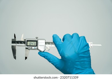 Quality control manufacturing.,Hands of blue gloved engineer measuring metal parts with digital vernier caliper in lab
 - Powered by Shutterstock