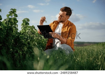 Quality control, with notepad. Handsome man is on the agricultural field at daytime.