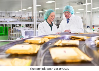 Quality control workers with digital tablet at production line in cheese processing plant