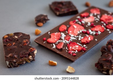 quality craft chocolate bars closeup, freeze-dried strawberry's chocolate bar among nut's chocolate pieces