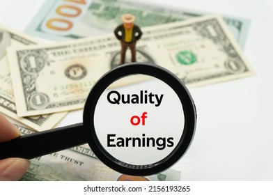 Quality of Earnings.Magnifying glass showing the words.Background of banknotes and coins.basic concepts of finance.Business theme.Financial terms.
