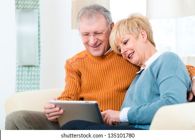 Quality Of Life - Two Elderly People Sitting At Home On The Couch And Writing Emails On The Tablet Computer