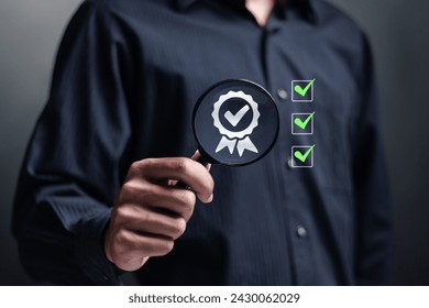 Quality management concept. Standardization certification. Compliance to regulations service and standards. Person use magnifying glass focus to Quality assurance icon on virtual screen. 