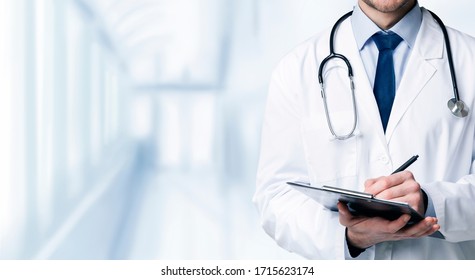 Quality Medical Services. Unrecognizable Male Doctor In Uniform Taking Notes To Clipboard While Standing In Hospital Corridor, Cropped Image, Panorama