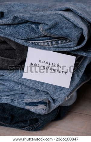 Quality not quantity text on paper note on Jeans clothes assortment Second hand sustainable shopping. Capsule minimal wardrobe. Sustainable fashion overconsumption, conscious buying consumption, slow