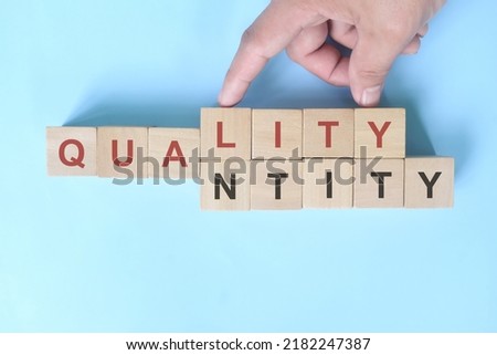 Quality over quantity concept. Hand changing word quantity to quality on wooden blocks.