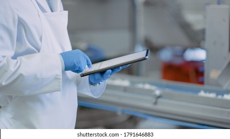 Quality Supervisor or Food Technician is Inspecting the Automated Production at a Food Factory. Close Up Shot of Employee Using Tablet Computer for Work. He Types In Data While Wearing Latex Gloves. - Shutterstock ID 1791646883