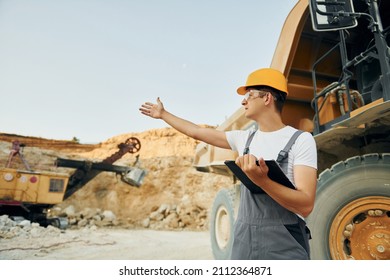 Quality vehicle. Worker in professional uniform is on the borrow pit at daytime.