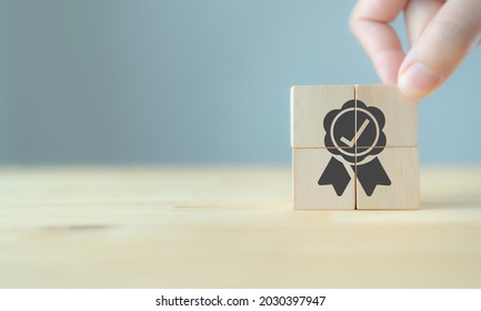 Quality warranty concept. Man's hand puts the wooden cubes with quality warranty icon on wooden cubes with grey background. Used for banner and advertising product and service quality commitment.