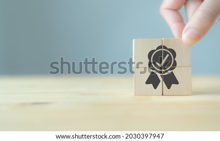 Quality warranty concept. Man's hand puts the wooden cubes with quality warranty icon on wooden cubes with grey background. Used for banner and advertising product and service quality commitment. Foto stock © 