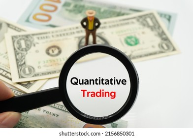 Quantitative Trading.Magnifying glass showing the words.Background of banknotes and coins.basic concepts of finance.Business theme.Financial terms. - Shutterstock ID 2156850301
