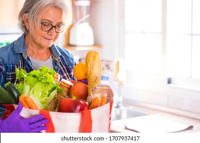 Quarantine For Coronavirus Covid-19 Pandemic. Casual Senior Woman With Protective Gloves Receives Grocery Delivery At Home With Basic Necessities. Concept Of Staying Home To Avoid Contagion