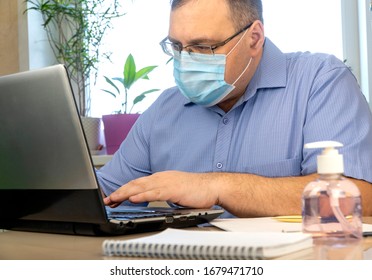 Quarantine Due Coronavirus Pandemic. Stay At Home. Business Man Working From Home, Wear A Protective Mask. Work From Home With Disinfectant Gel. Remote Work, Learning Due To The Epidemic COVID-19.