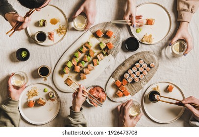 Quarantine Japanese Sushi Dinner From Delivery Or Takeaway Service At Home. Flat-lay Of People Eating Salmon, Crab, Prawn Rolls Variety, Wasabi, Ginger Over Light Tablecloth Background, Top View