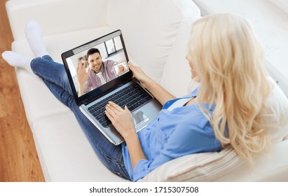 quarantine, technology and online communication concept - young woman with laptop computer sitting on couch at home and having video call with man