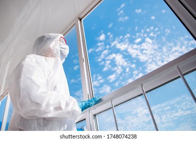 Quarantined Woman In Mask On Self-isolation In Apartment Looks Out Balcony Window Blue Sky And Clear Air.