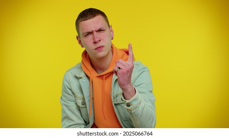 Quarrel. Displeased teenager boy gesturing hands with irritation and displeasure, blaming scolding for failure, asking why this happened. Young man indoors studio shot on yellow wall background