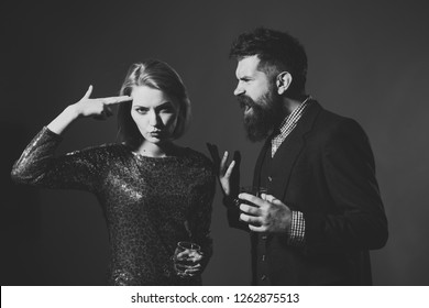 Quarrel And Relations Concept. Couple Quarreled At Corporate Party. Woman Fed Up With Quarrel In Fancy Dress And Man Screaming On Blue Background. Girl With Gun Gesture Holds Wineglass With Wiskey.