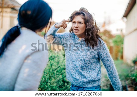 Quarrel two friends. Two women screaming at each other. Two young women argue. Family problem. Angry. Female. Nature background. Emotional. Emotion. Depression. People. Stress. Family photo. 
