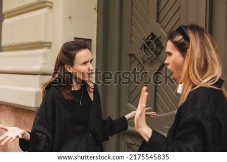 Quarrel two friends. Two women screaming at each other. Two young women argue near door outdoor on the street. Family problem. Angry female show emotion. Depression people. Stress family photo.