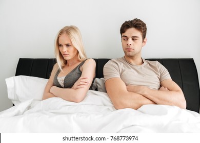 Quarreled Couple, Blonde Woman And Hansome Upset Man, Sitting In Bed And Don't Looking At Each Other At Home