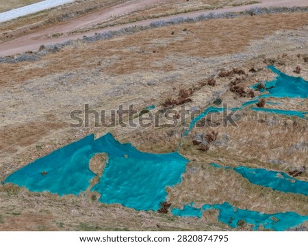 Quarry material piles with stepped surface covered by vegetation and worn shade netting