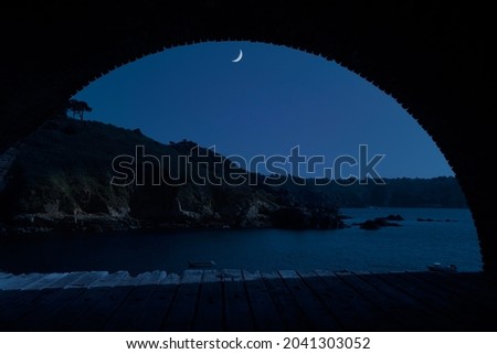 Quarter moon over Saints Bay Harbor in Guernsey, an island in the English Channel