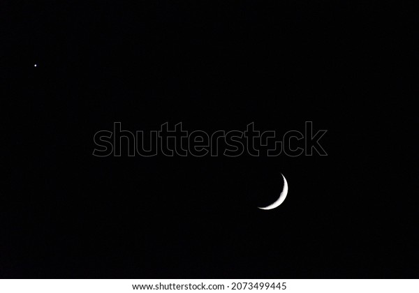 Quarter moon and\
the planet Venus in a black\
sky