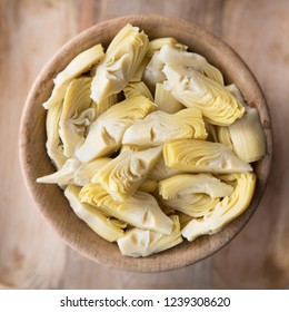 Quartered artichoke hearts in wooden bowl viewed from above
