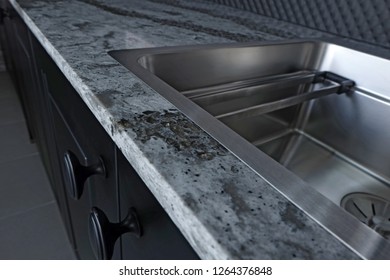 Quartz Counter Worktop With Beautiful Pattern And Stainless Steel Sink On Black Wooden Kitchen.