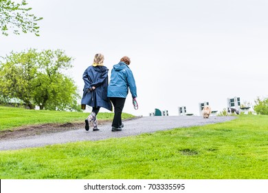Quebec City, Canada - May 30, 2017: Two women walking on trail path street in plains d'Abraham in morning during rainy day with dogs