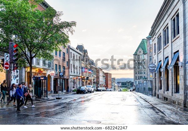 Quebec City,\
Canada - May 31, 2017: Old town street with people crossing Cote du\
Palais road and view of\
sunset