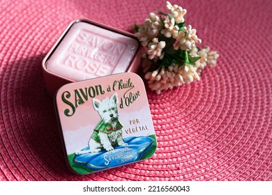 Quebec City, Quebec, Canada, October 20, 2022 - Pure Olive Oil And Essence Of Rose Square Soap From French Producer La Savonnerie De Nyons In Open Metal Box With Image Of White Dog On Pink Background