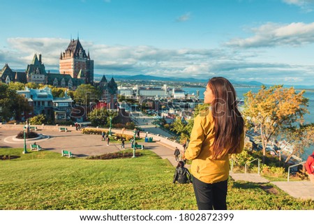 Quebec city Canada travel destination. Asian woman tourist walking sightseeing looking at view of St Lawrence river and Chateau Frontenac Castle, popular destination for Autumn traveling.